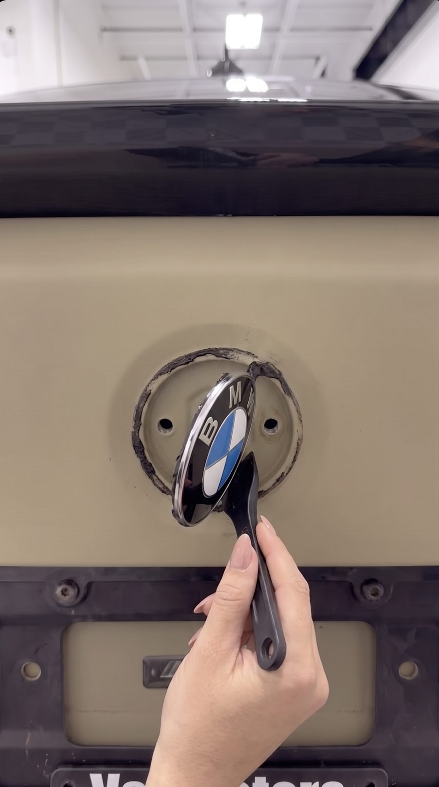 Prying the factory roundel off with a plastic trim tool
